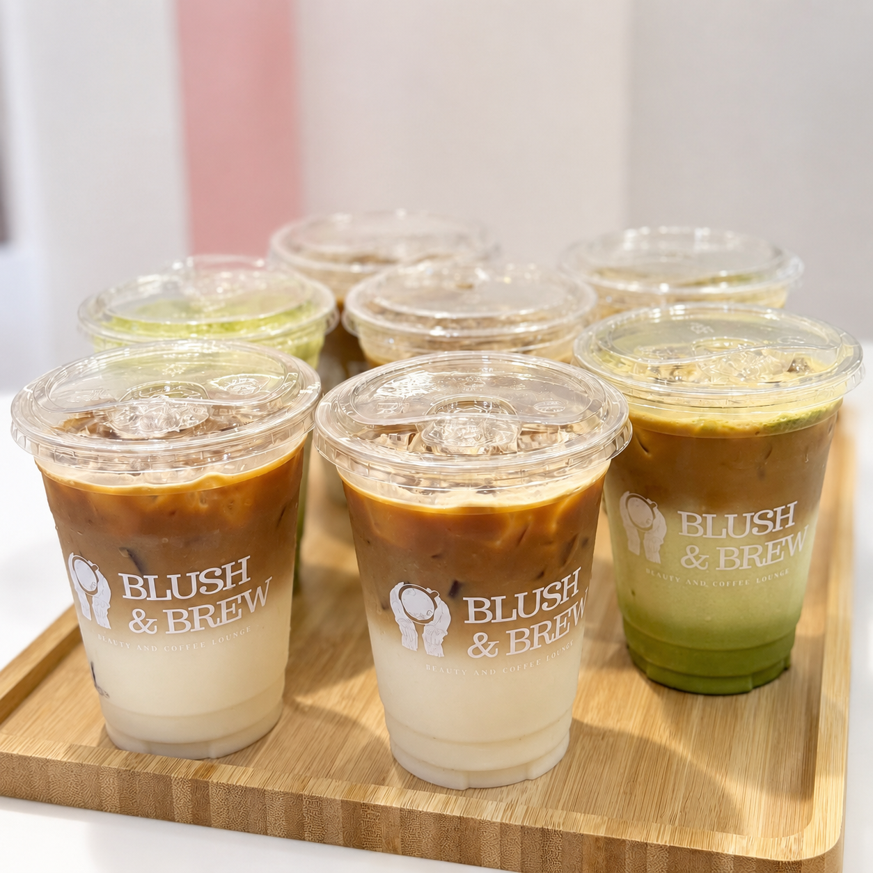 Selection of iced coffee and green specialty drinks served in Blush & Brew cups.